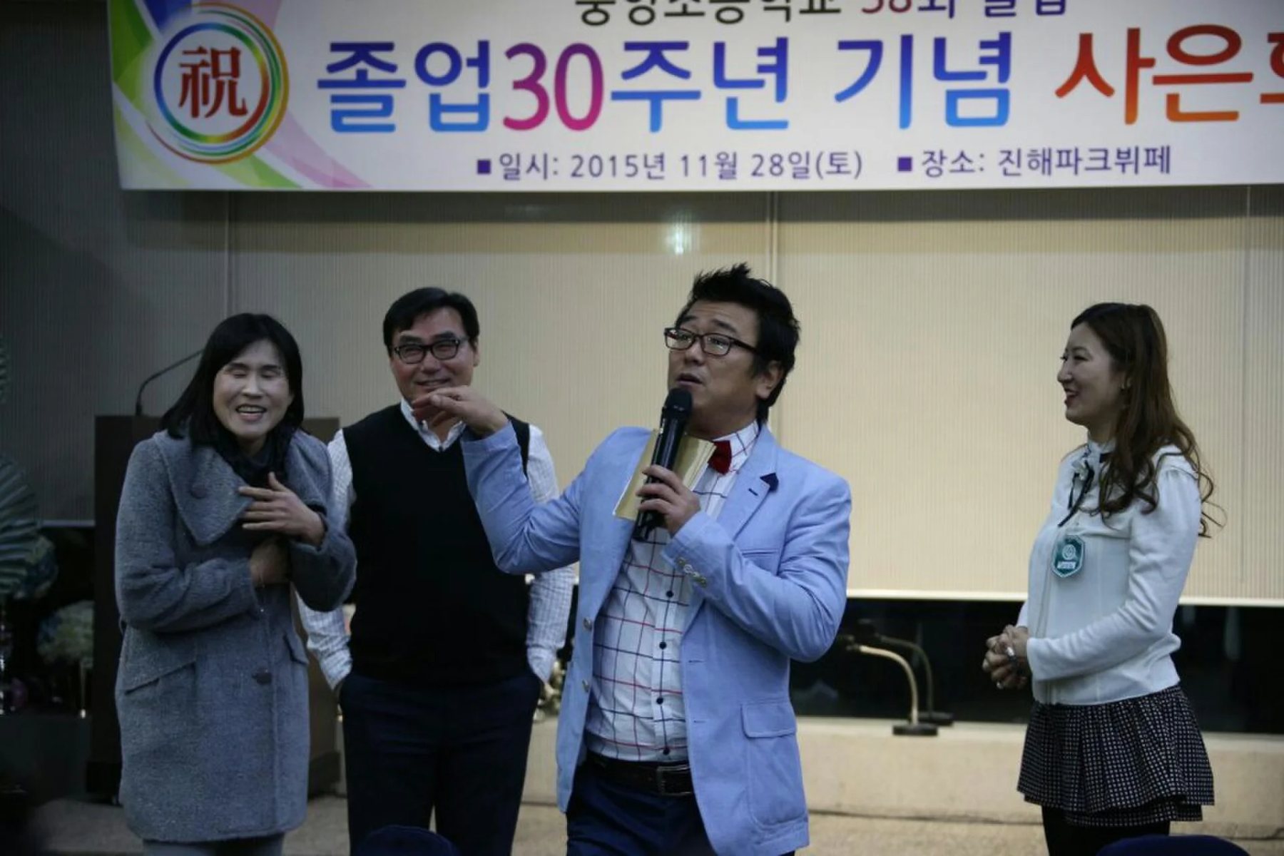 시상식 사회자 프로필 현장, 실내 마이크를 든 현수막이 걸린 신용주 진행 모습 (mc-portrait-02)