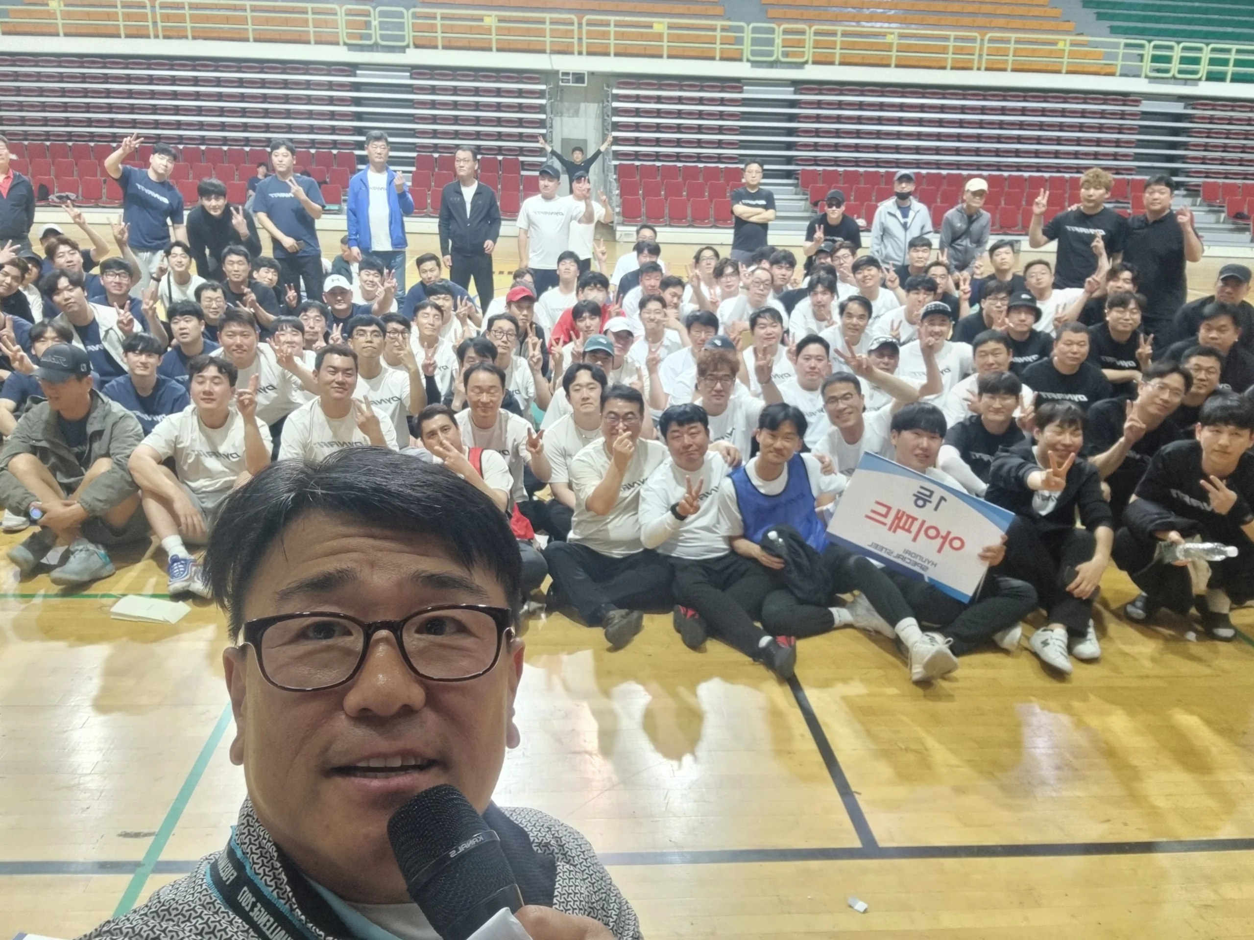 경진대회 시상식 사회자 현장, 국기 장식이 걸린 실내 체육관 무대 전경 (mc-wide-30)